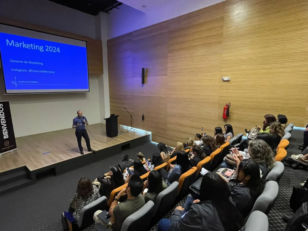 Marcus da Fonseca no palco de um auditório, falando para a plateia com o slide Marketing 2024